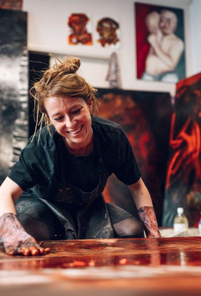 Female painter artist creating her art in a creative studio on a big canvas with her hands and oil paint. Artist on the work. Contemporary painter creating colorful, emotional, sensual oil painting.